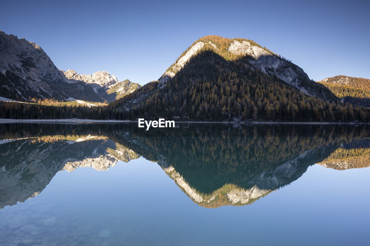 Scenic view of lake and mountains against clear blue sky