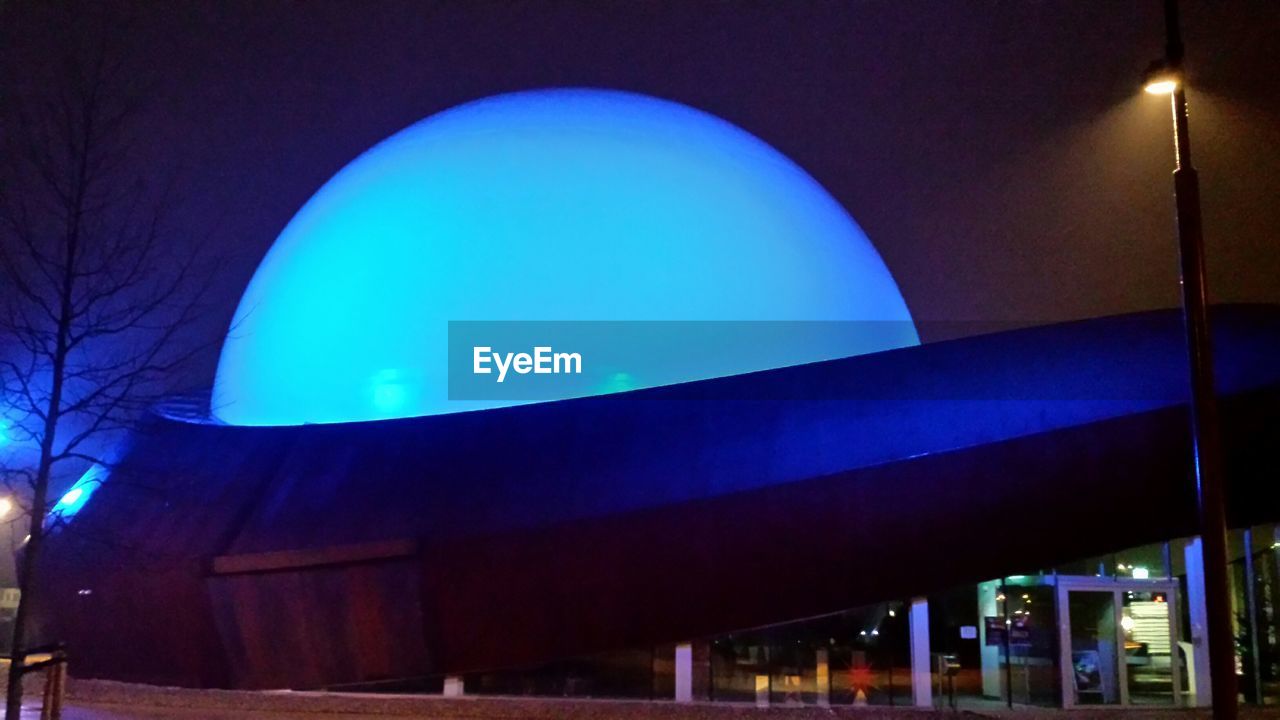 LOW ANGLE VIEW OF ILLUMINATED BUILT STRUCTURE AGAINST BLUE SKY