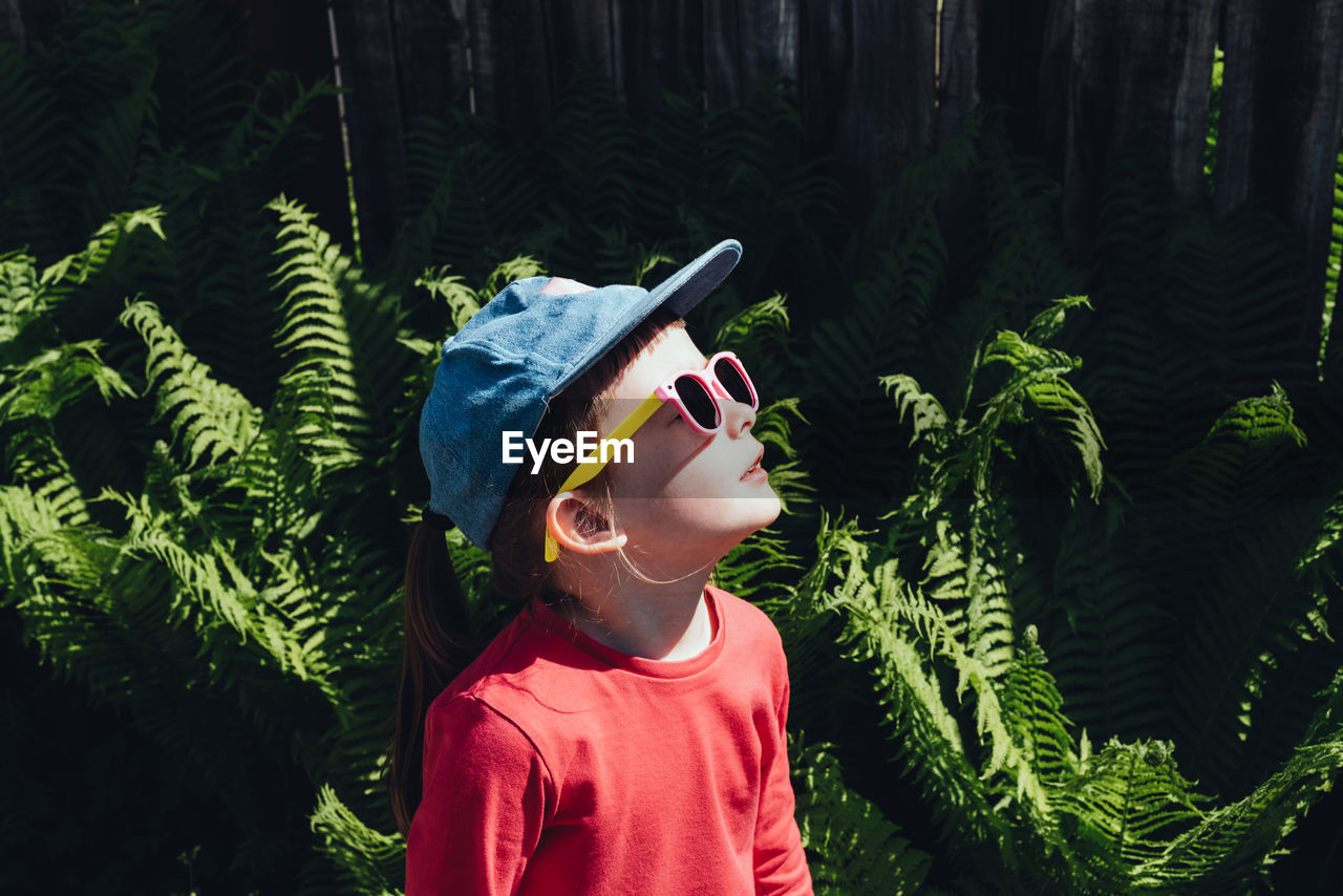 Happy child looking up at the sun in sunglasses and a cap. the concept of mental health, self-care 