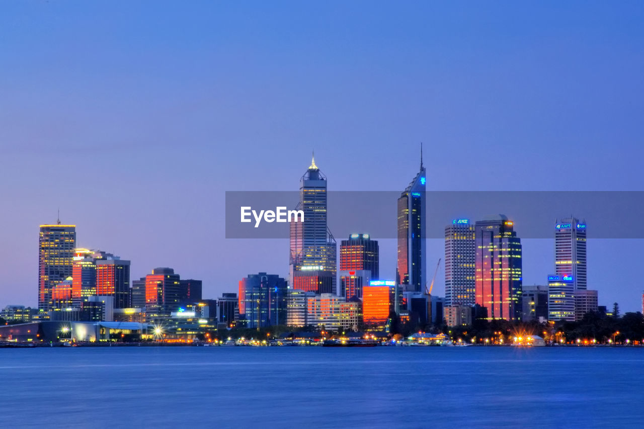 Illuminated city against clear sky at dusk