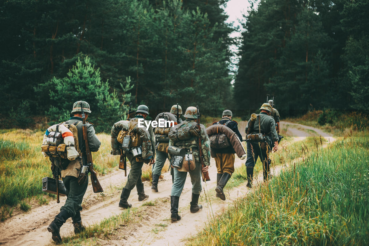 Rear view of soldiers walking on trail in forest