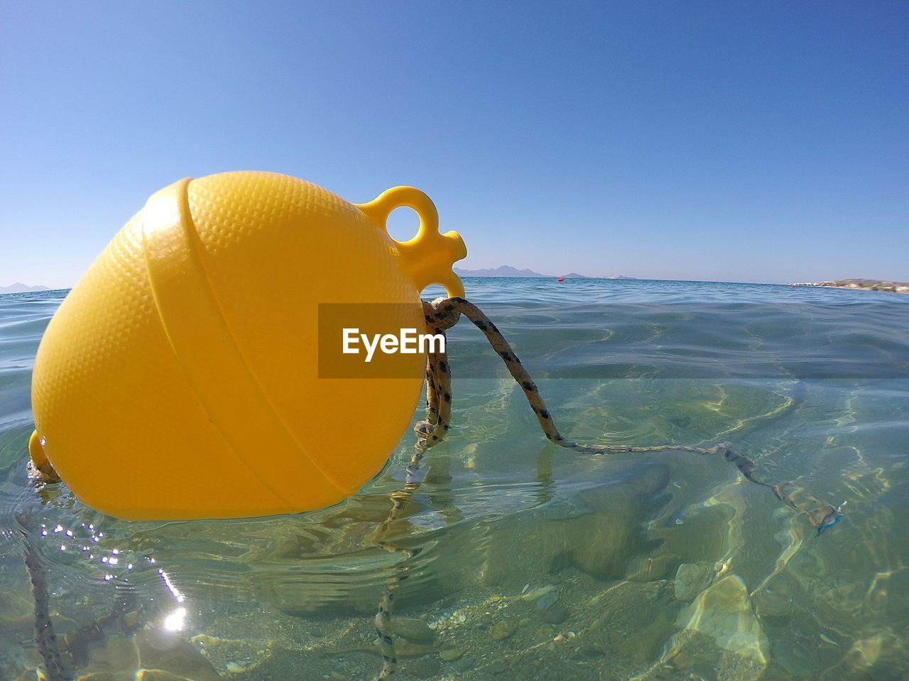 CLOSE-UP OF YELLOW UMBRELLA ON BEACH AGAINST CLEAR SKY