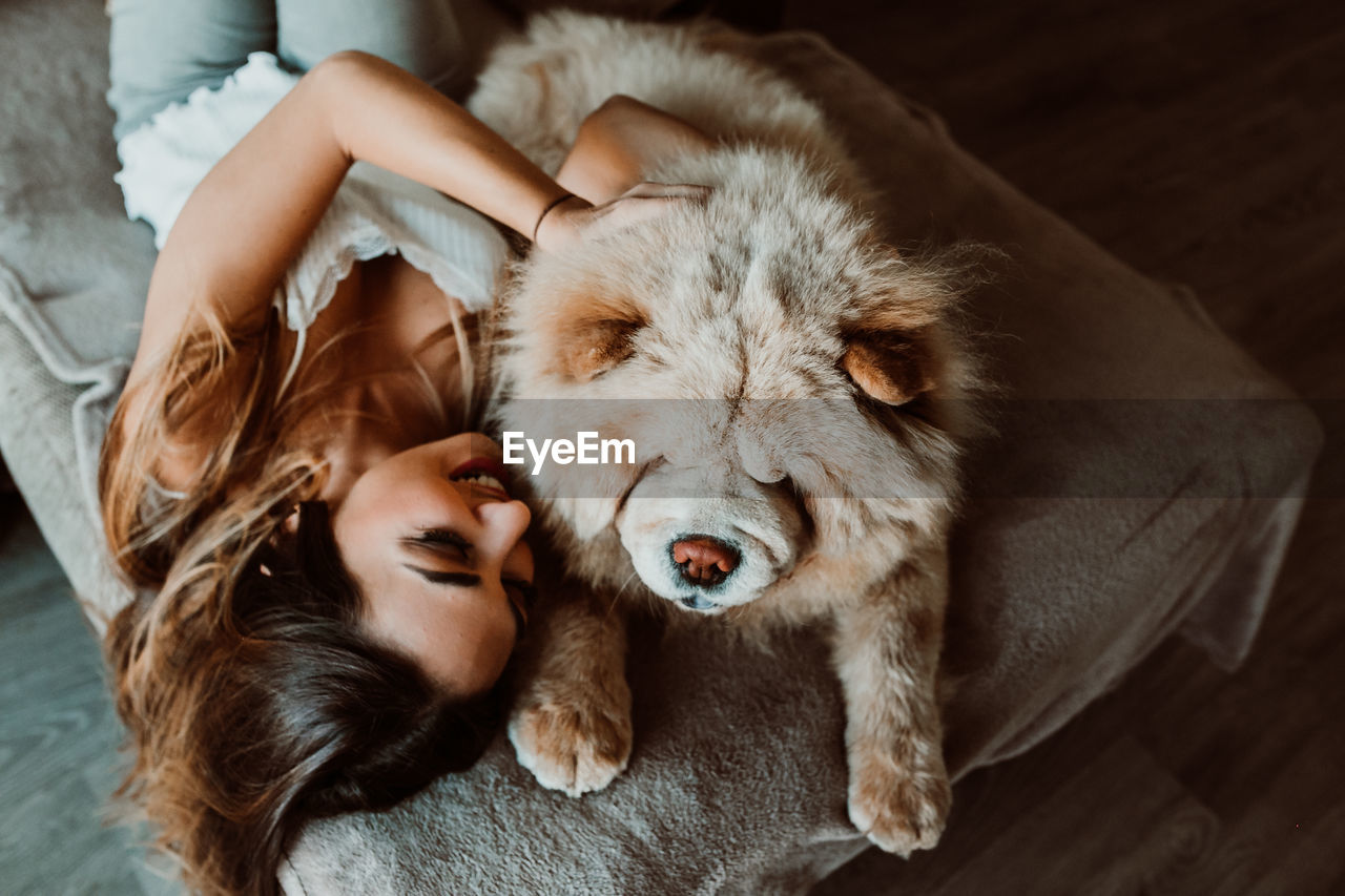 High angle view of young woman with dog lying on bed at home