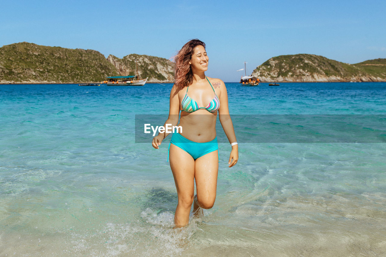 FULL LENGTH OF YOUNG WOMAN AT BEACH