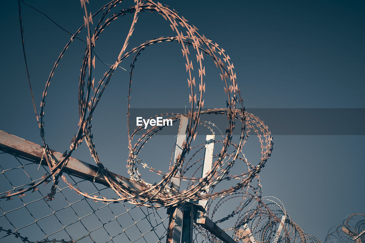 LOW ANGLE VIEW OF WIRE FENCE AGAINST CLEAR SKY