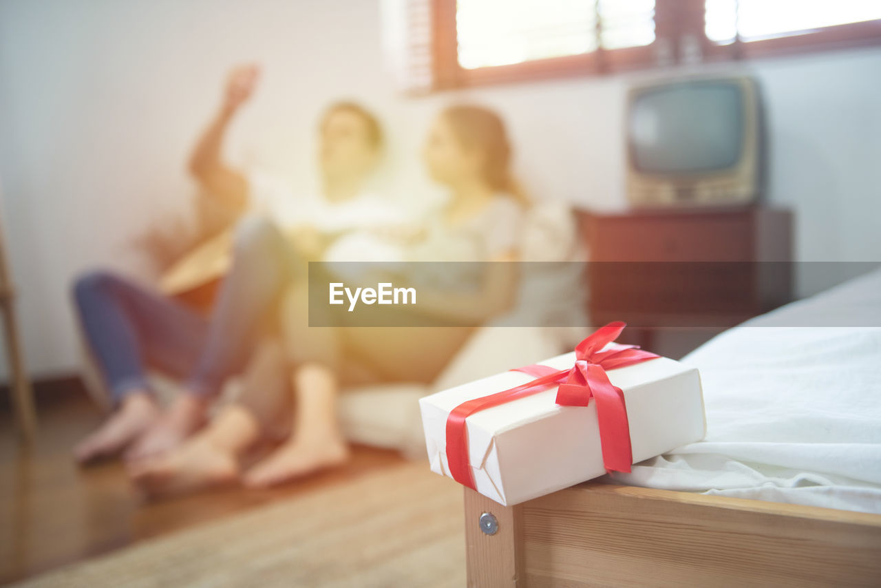 Gift box with blurred caucasian couple in background.