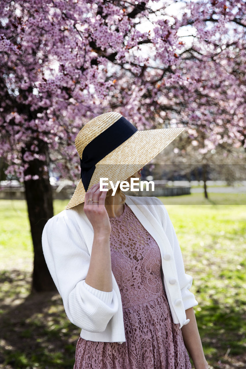 LOW SECTION OF WOMAN STANDING BY PINK CHERRY BLOSSOM