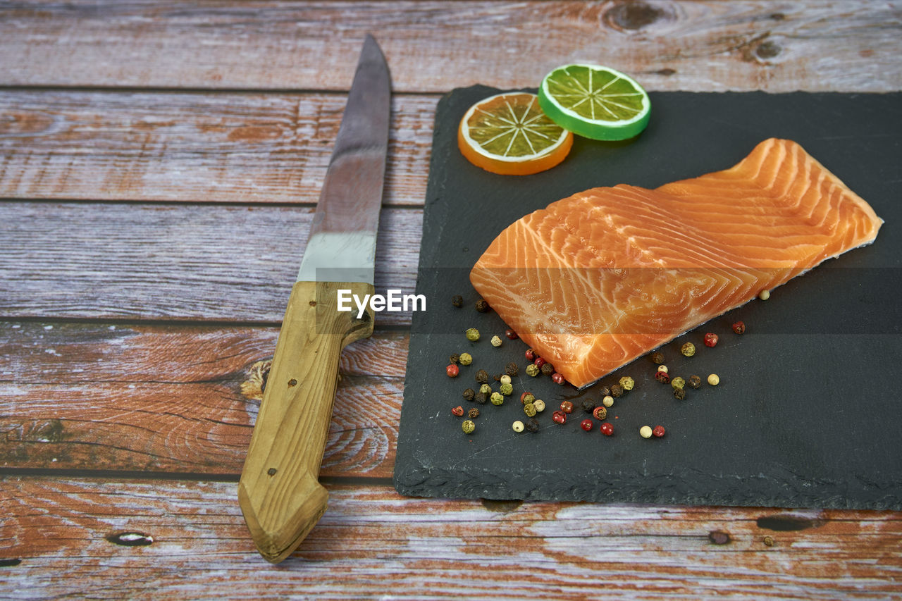 Fresh salmon fillets on black cutting board with herbs and spice