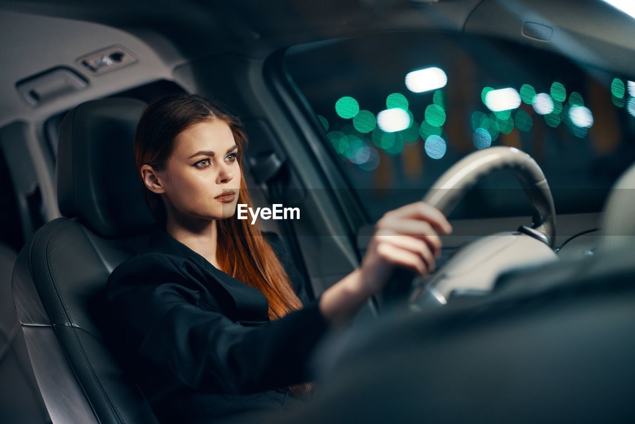 Confident young woman driving car