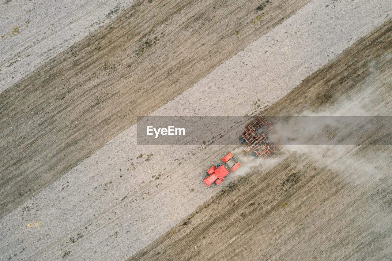 Spring plowing field red tractor aerial photography with drone. 