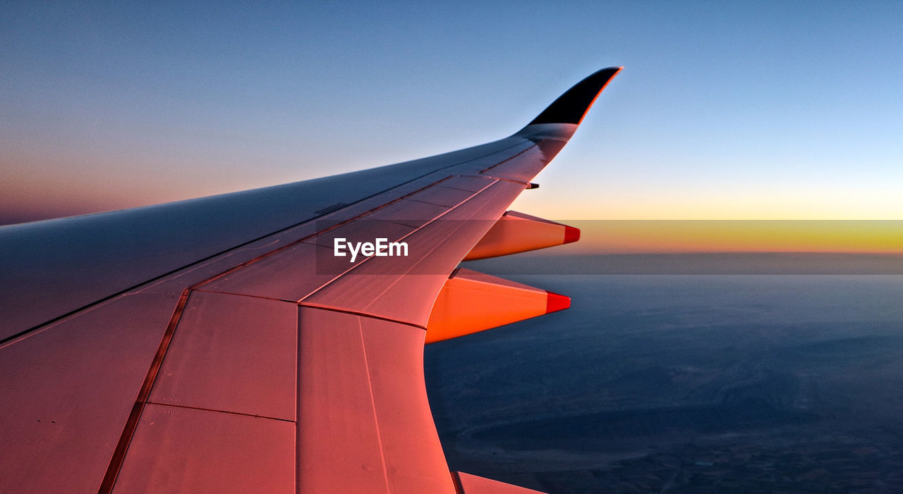 Airplane flying over sea against sky during sunset