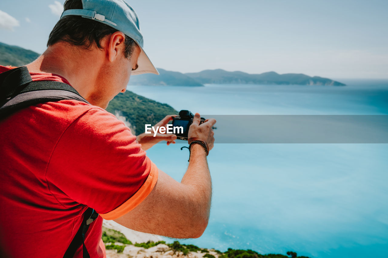 Rear view of man photographing sea against sky