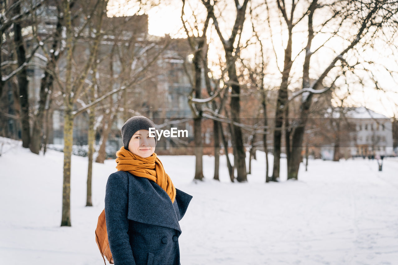 A woman on the street of a winter city looks into the camera