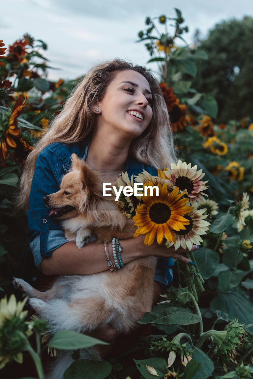 Young woman holding dog and flowers