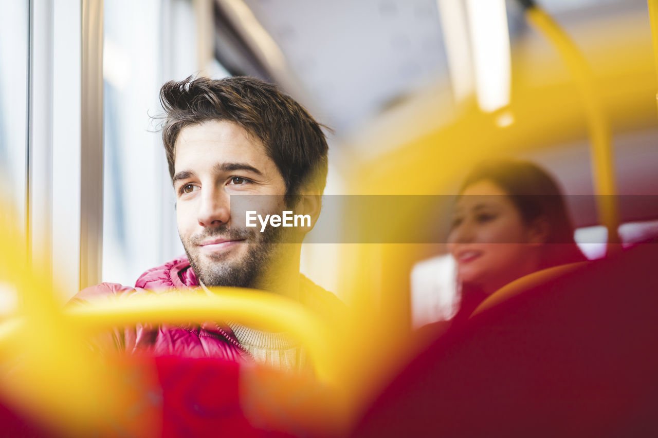 Uk, london, portrait of smiling young man in bus looking out of window