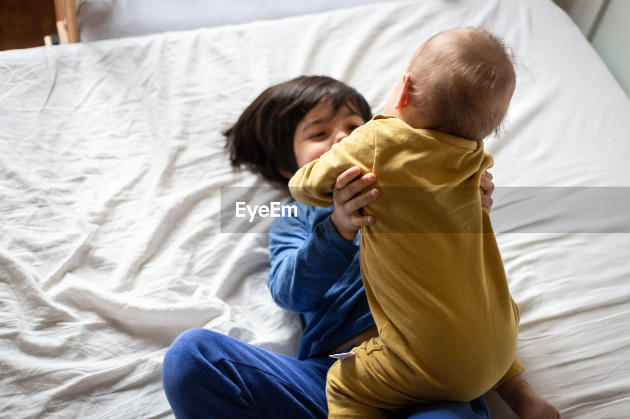 High angle view of two happy children hugging each other on the parent's bed