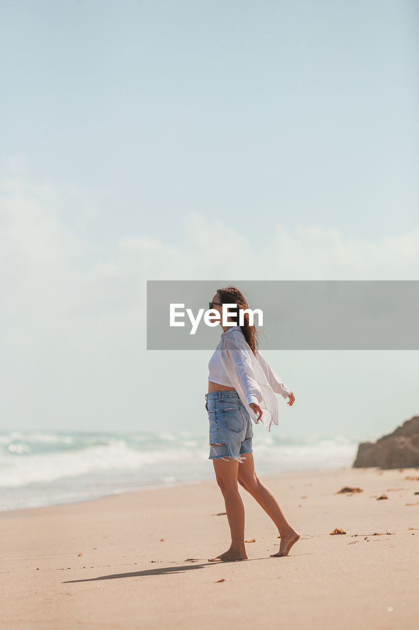 portrait of young woman standing at beach