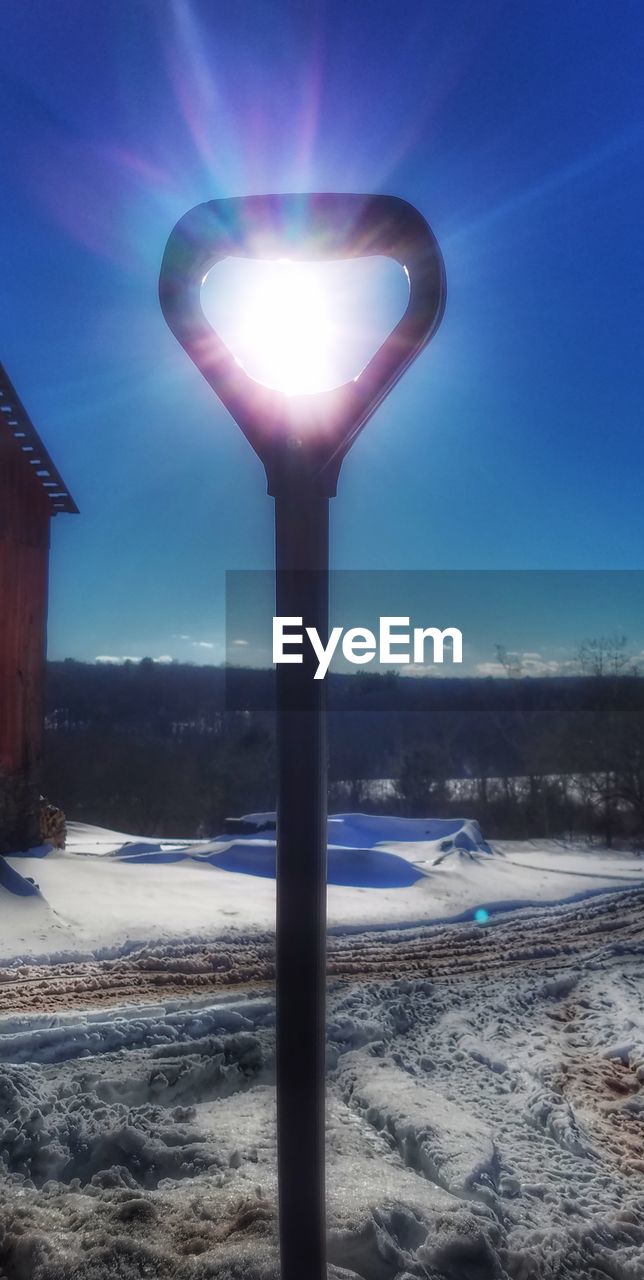 ILLUMINATED STREET LIGHT ON SNOW COVERED LANDSCAPE AGAINST BLUE SKY