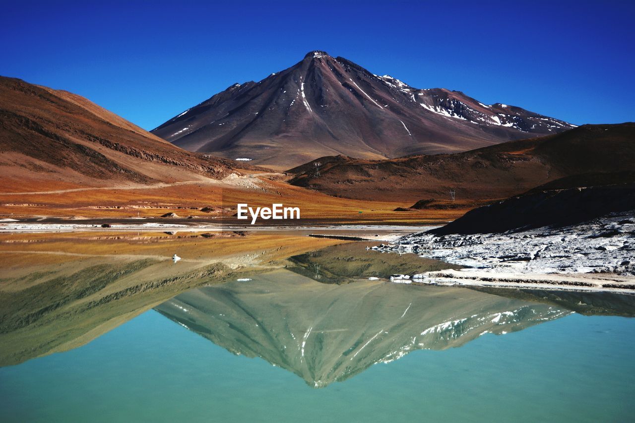 Scenic view of lake and mountains against clear blue sky