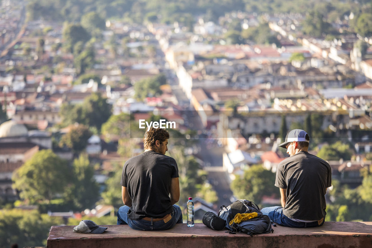 Tourists sit on bench at hill of the cross overlooking antigua