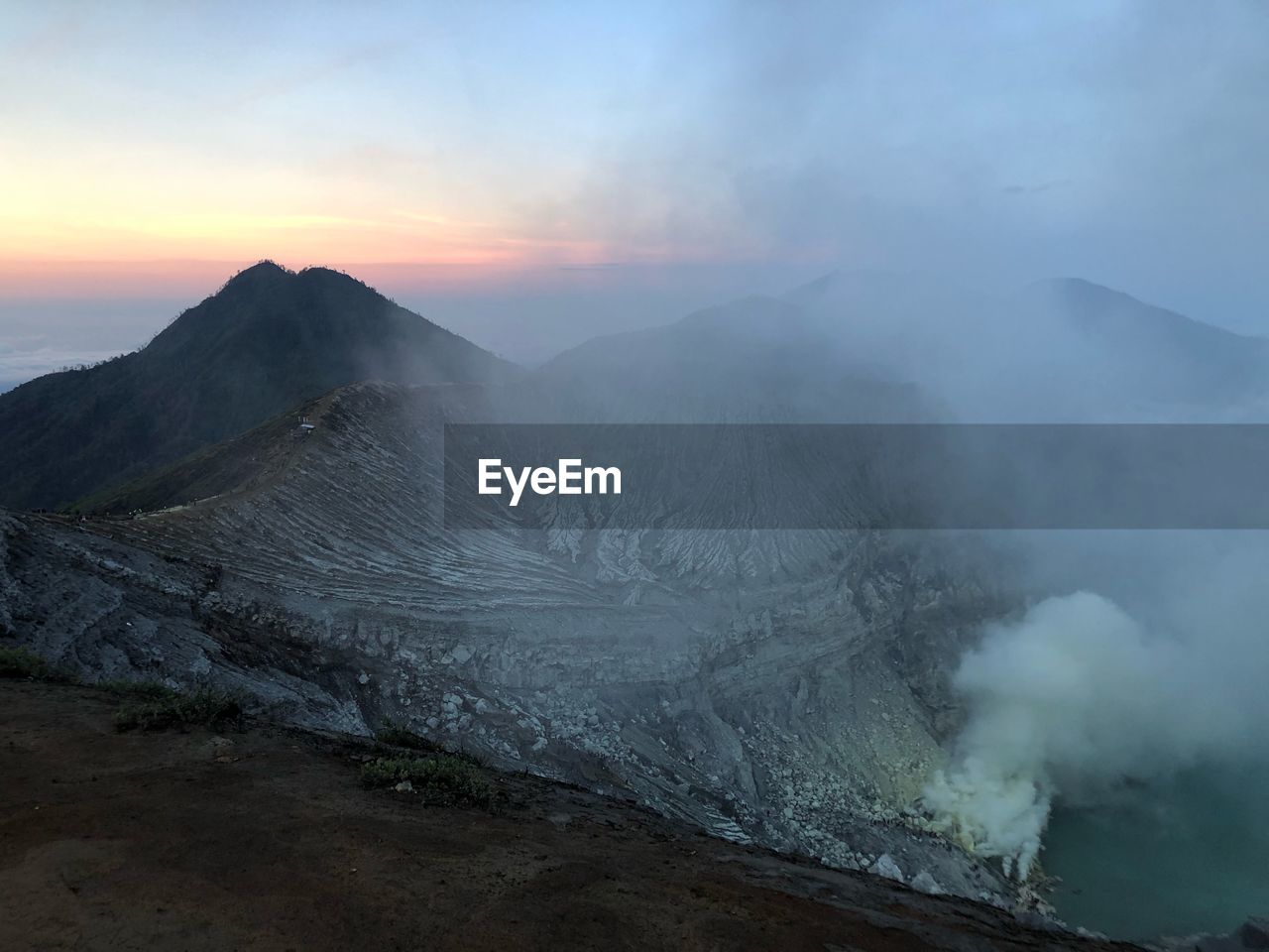 SMOKE EMITTING FROM VOLCANIC LANDSCAPE AGAINST SKY