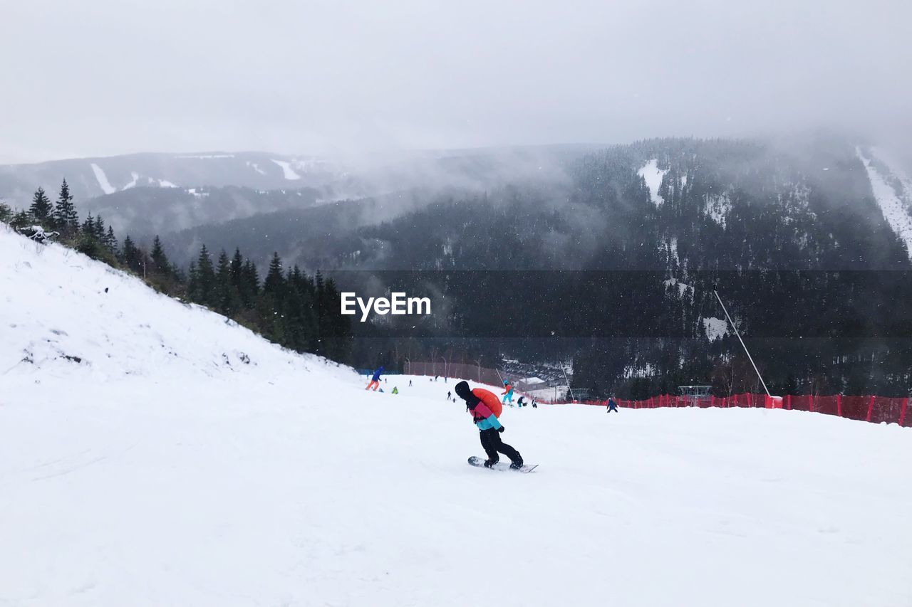 MAN SKIING ON SNOWCAPPED MOUNTAIN AGAINST SKY