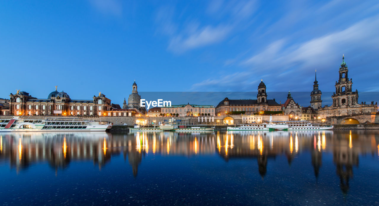 Boats moored on river by dresden frauenkirche at dusk