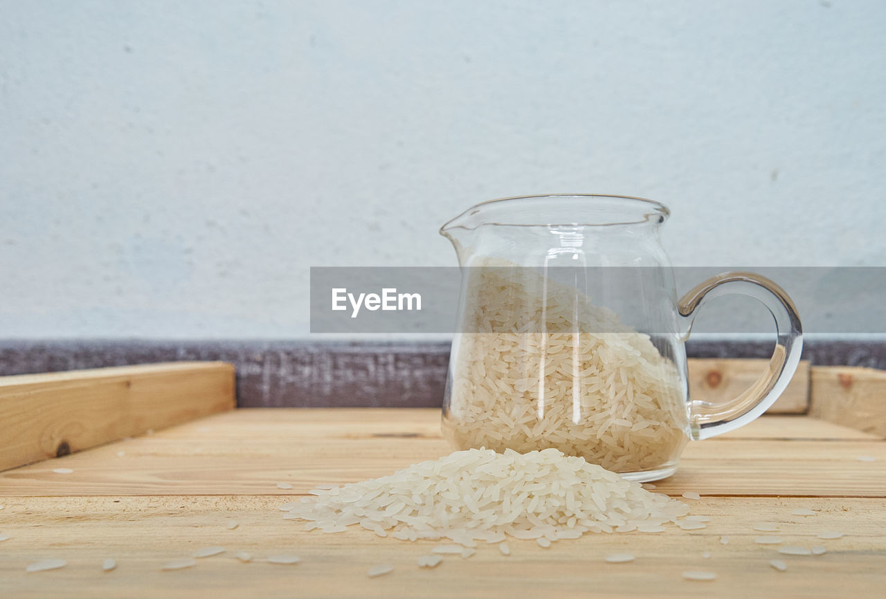 Close-up of rice in container on wooden table