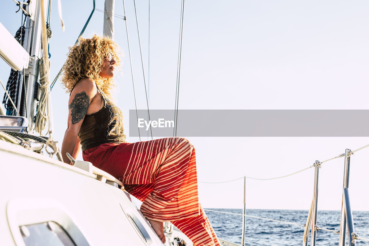 Woman sitting on boat in sea against sky