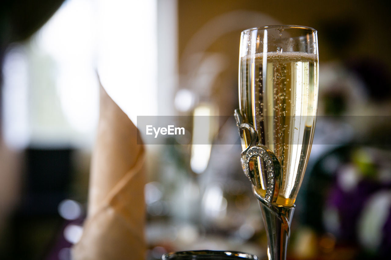CLOSE-UP OF WINE GLASS WITH BEER IN BACKGROUND