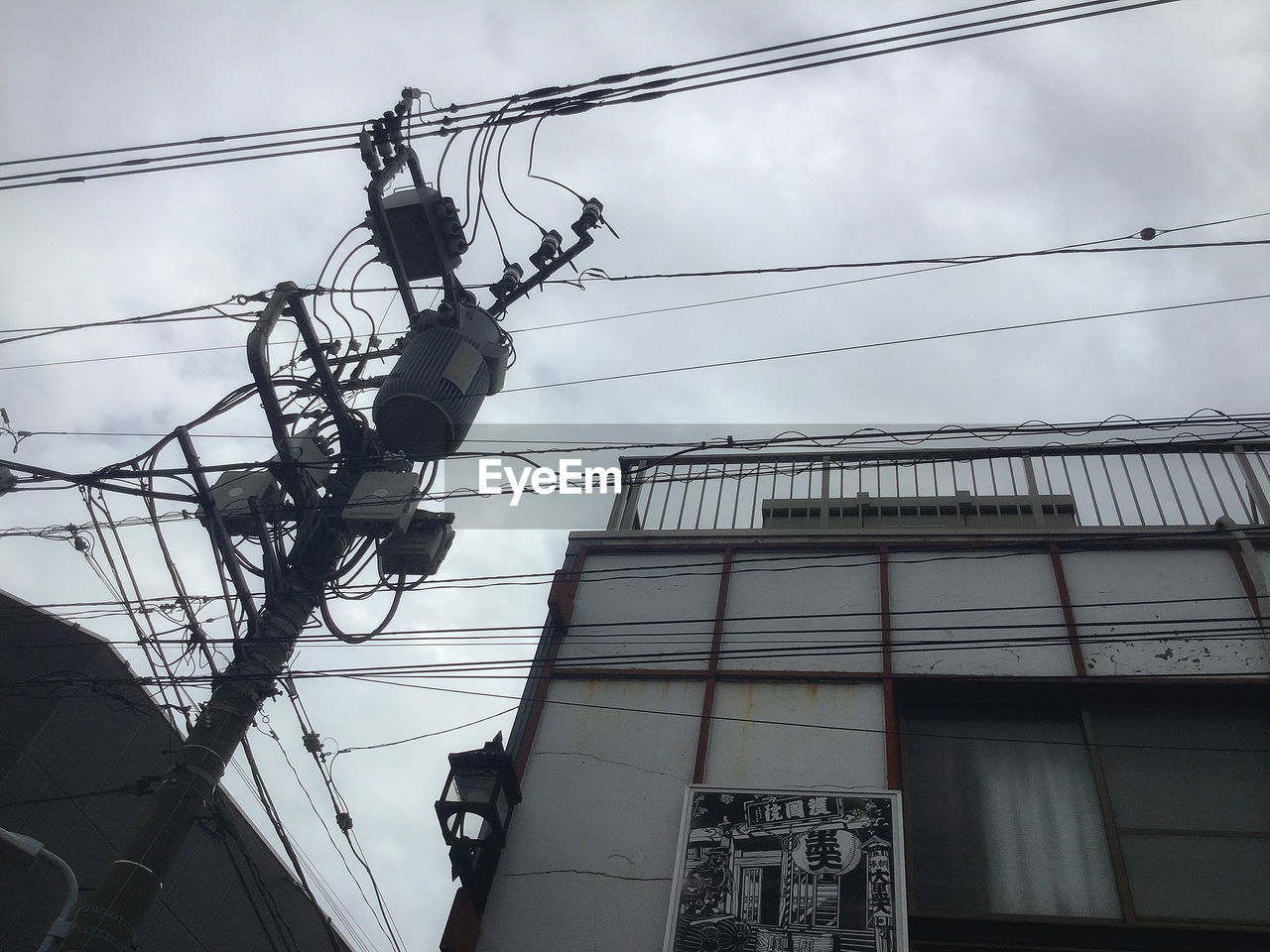 LOW ANGLE VIEW OF ELECTRICITY PYLON AGAINST BUILDING