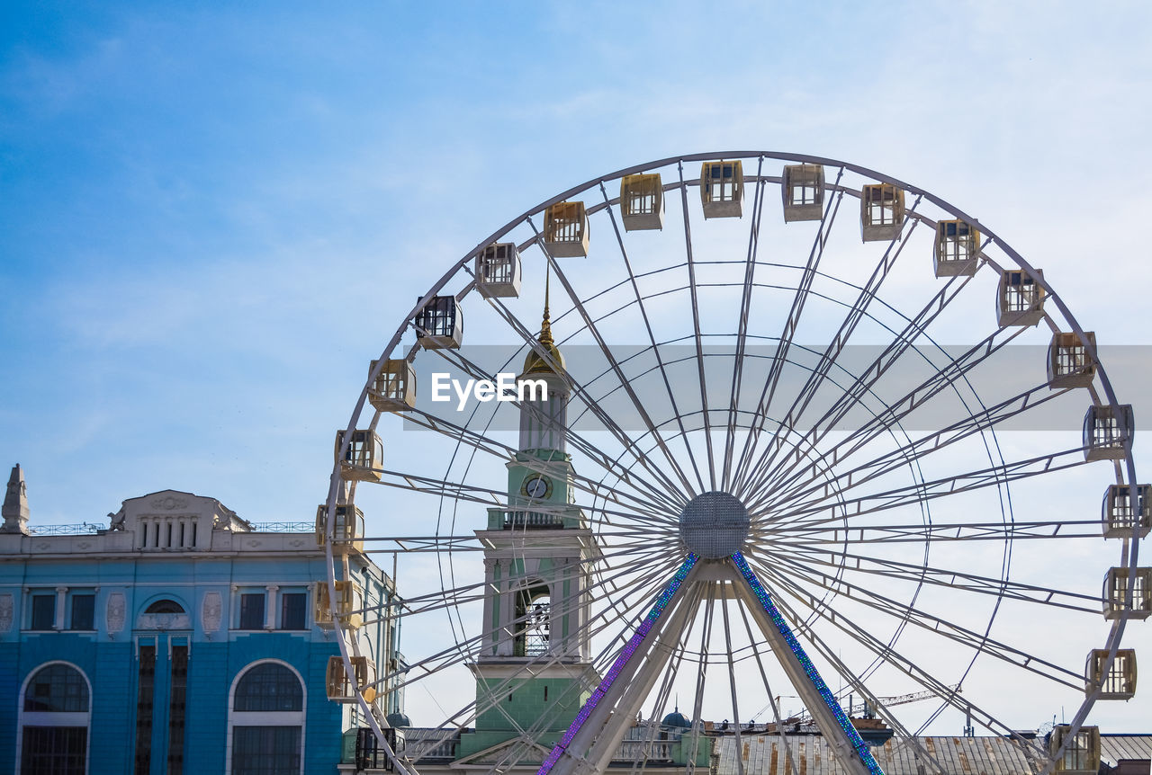 LOW ANGLE VIEW OF FERRIS WHEEL AGAINST BUILDING