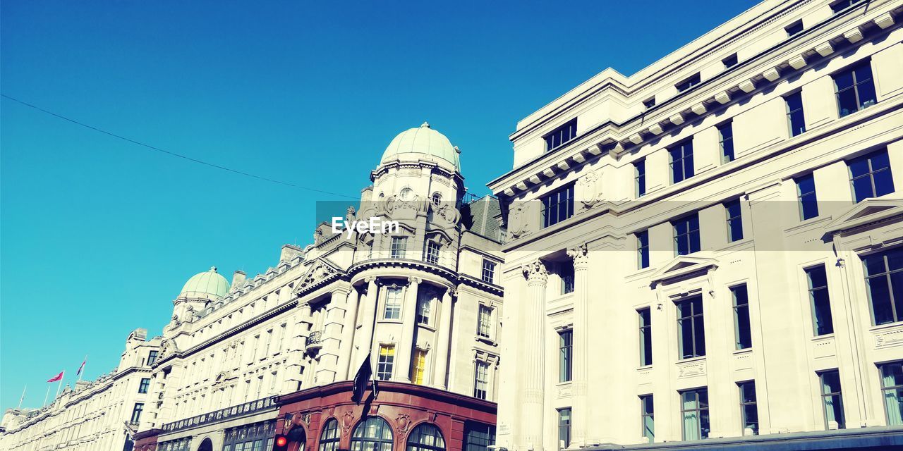 LOW ANGLE VIEW OF BUILDINGS AGAINST BLUE SKY