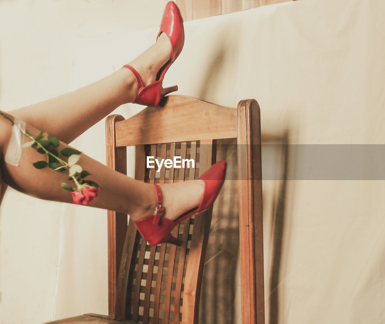 Legs of woman in red red upside down  against wall