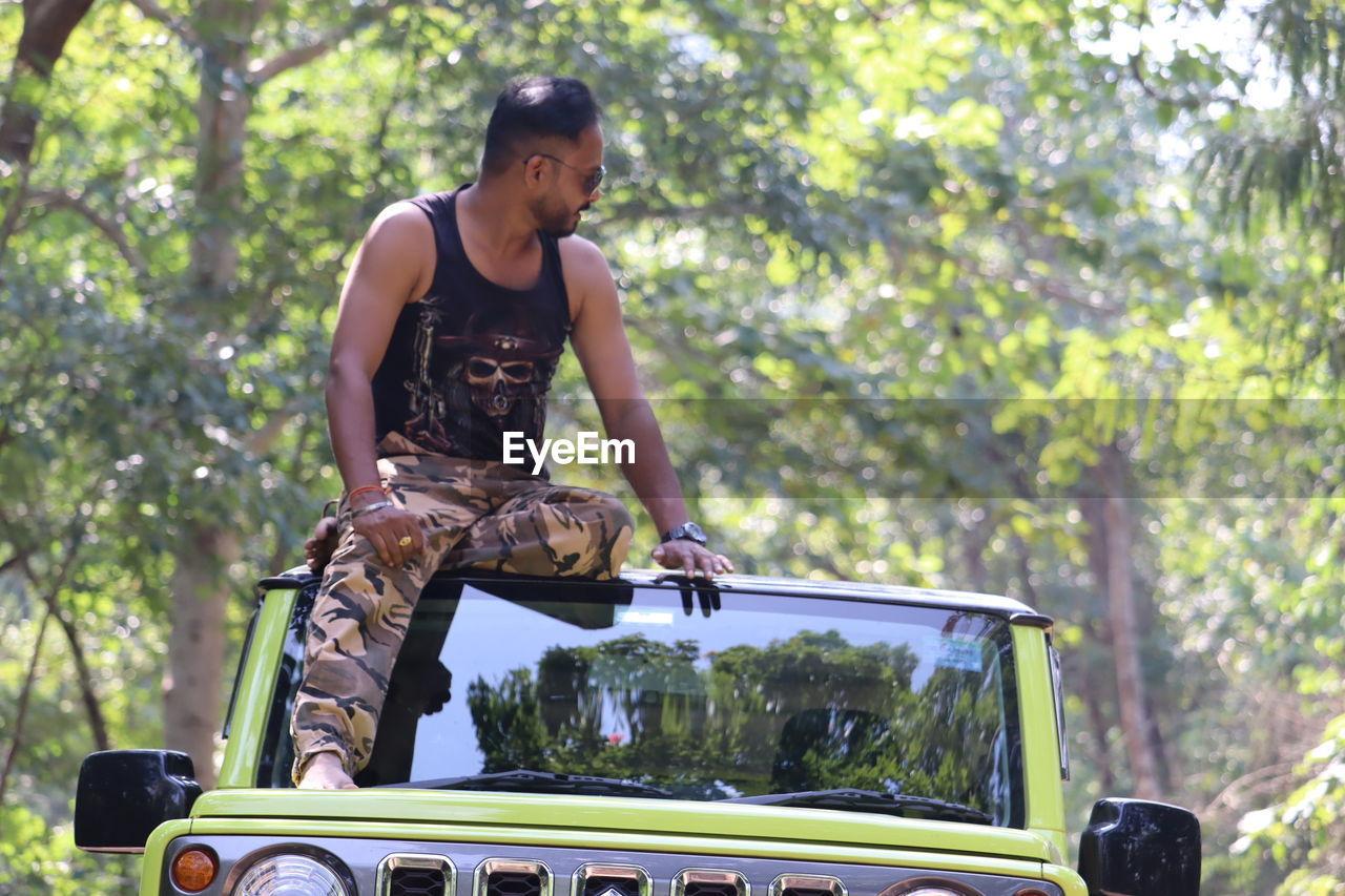 one person, adult, tree, transportation, mode of transportation, car, plant, young adult, nature, lifestyles, off-roading, forest, motor vehicle, men, day, vehicle, outdoors, casual clothing, sports, person, three quarter length, leisure activity, land, clothing, land vehicle