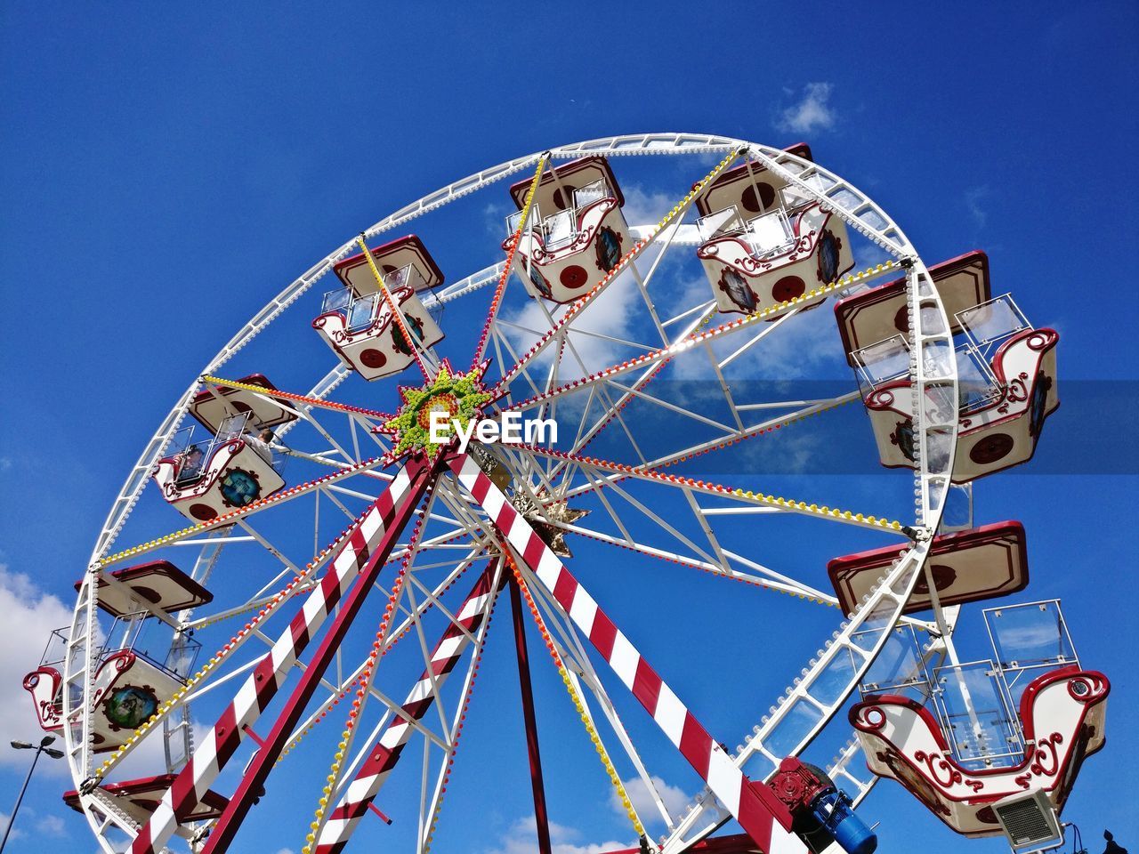 Low angle view of ferris wheel against blue sky during sunny day