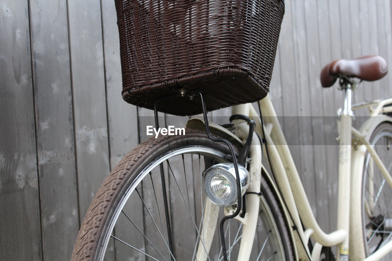 CLOSE-UP OF BICYCLE LEANING ON WOOD AGAINST WALL