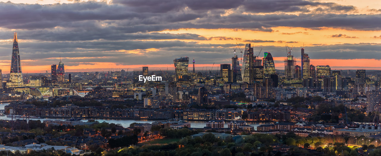 Panoramic view of cityscape against cloudy sky during sunset