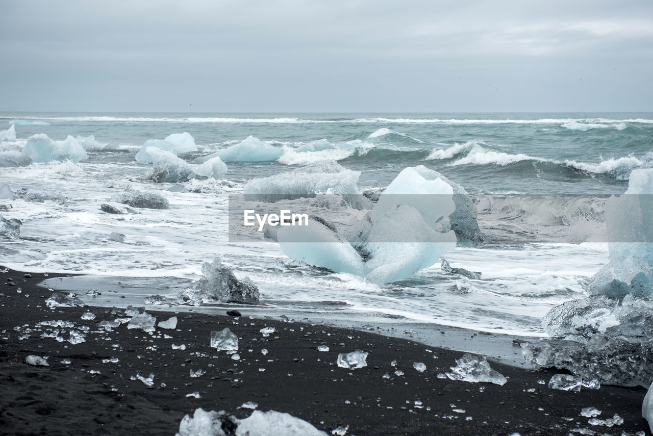 Ice blocks on diamond  beach, sea waves, black sand. jokulsarlon. atlantic ocean coast, iceland