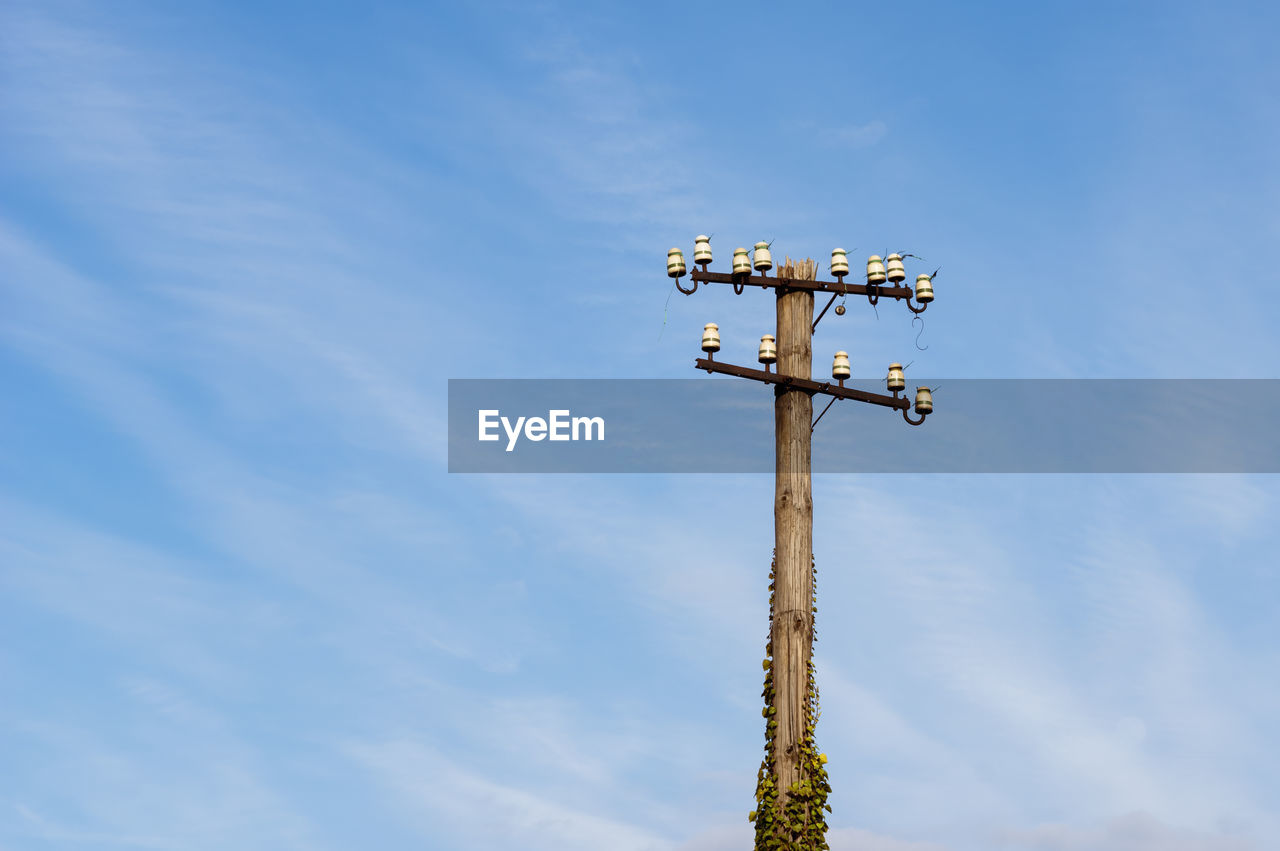 Low angle view of old and decaying telegraphy pole at a train station in germany against blue sky