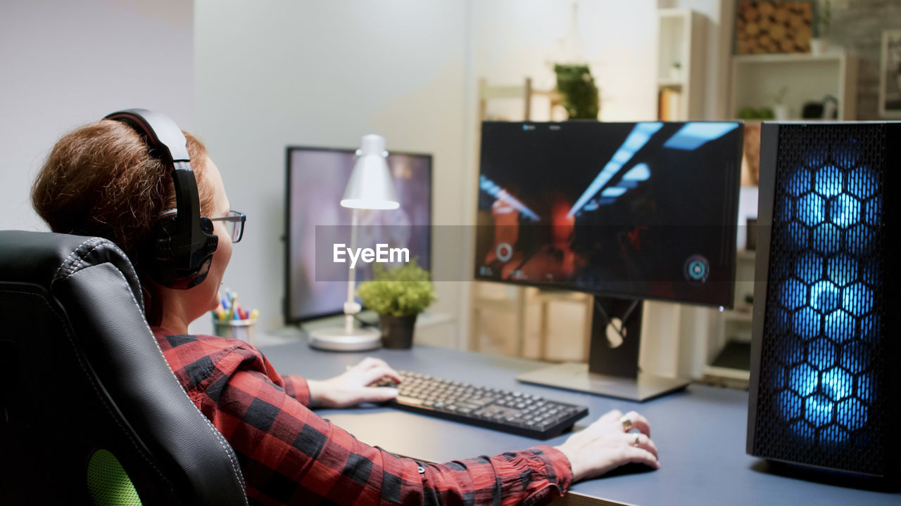 rear view of woman using laptop while sitting at home