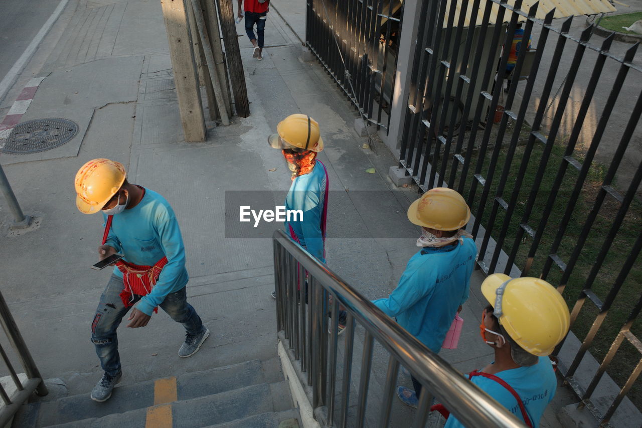 HIGH ANGLE VIEW OF MEN WORKING ON RAILING