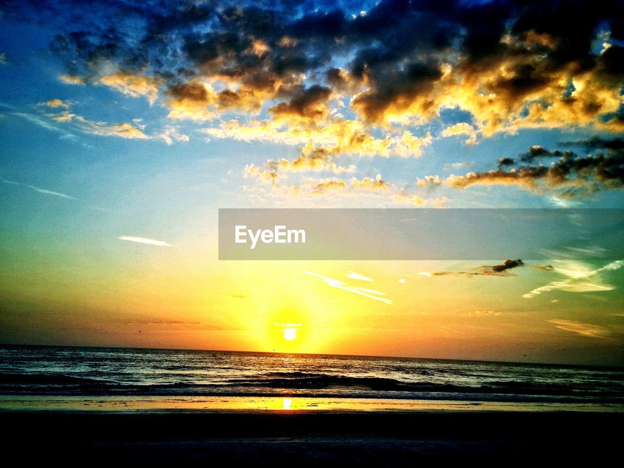 Scenic shot of sea against cloudy sky during sunset