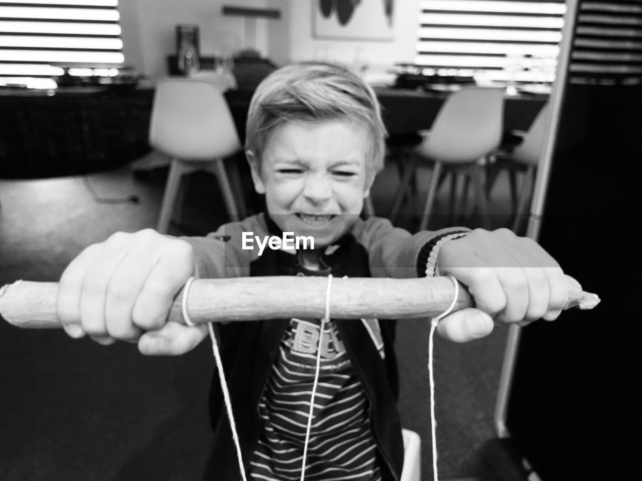 Boy holding stick with strings at home