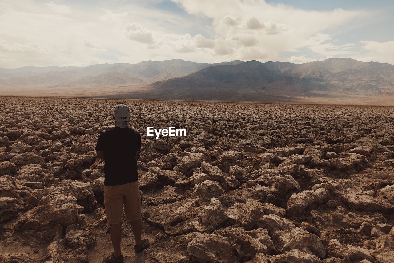 Rear view of man standing on landscape against sky