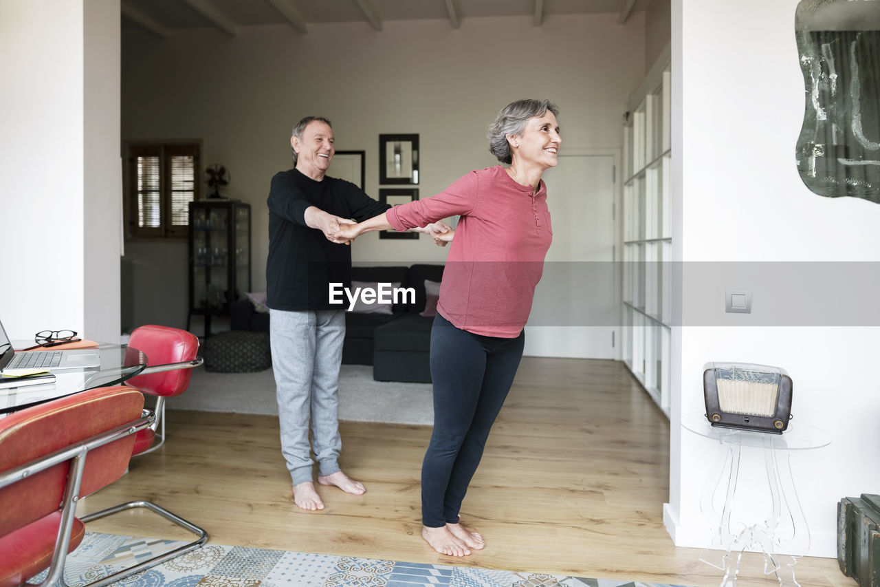 Senior man assisting woman in doing yoga