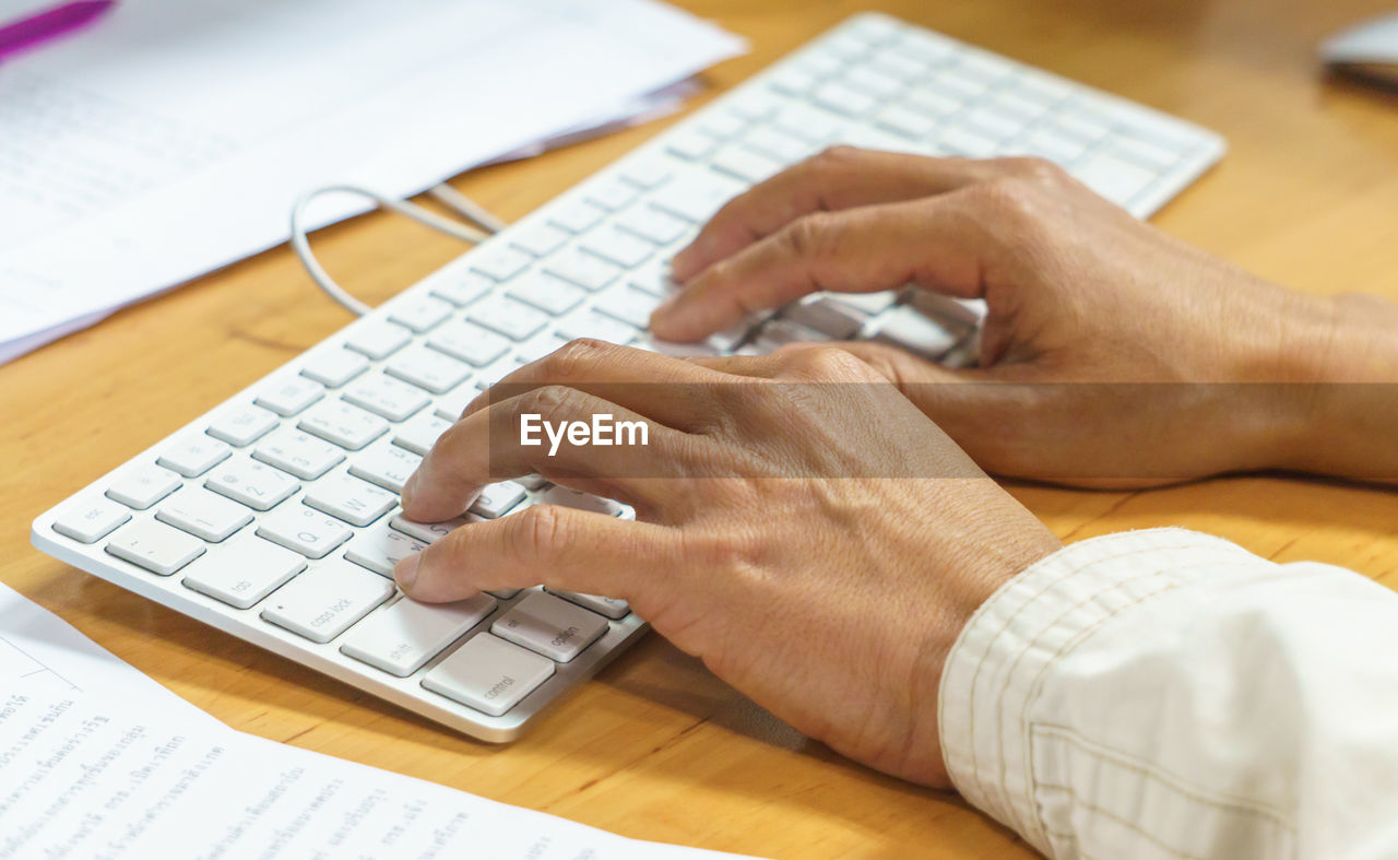 Cropped hands of businessman typing on keyboard in office