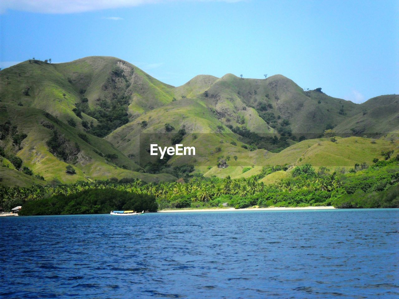 Scenic view of sea and mountains against clear blue sky