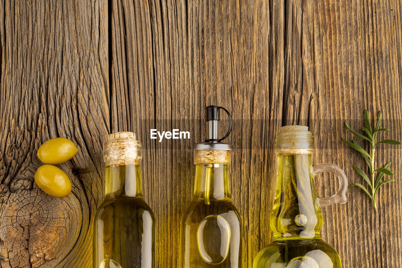 food and drink, yellow, wood, container, food, bottle, no people, wine bottle, still life, drink, fruit, freshness, refreshment, indoors, glass bottle, olive oil, glass, alcohol, table, healthy eating, lemon, plant, oil, cooking oil, spice, wellbeing, herb, close-up, citrus fruit, produce, high angle view