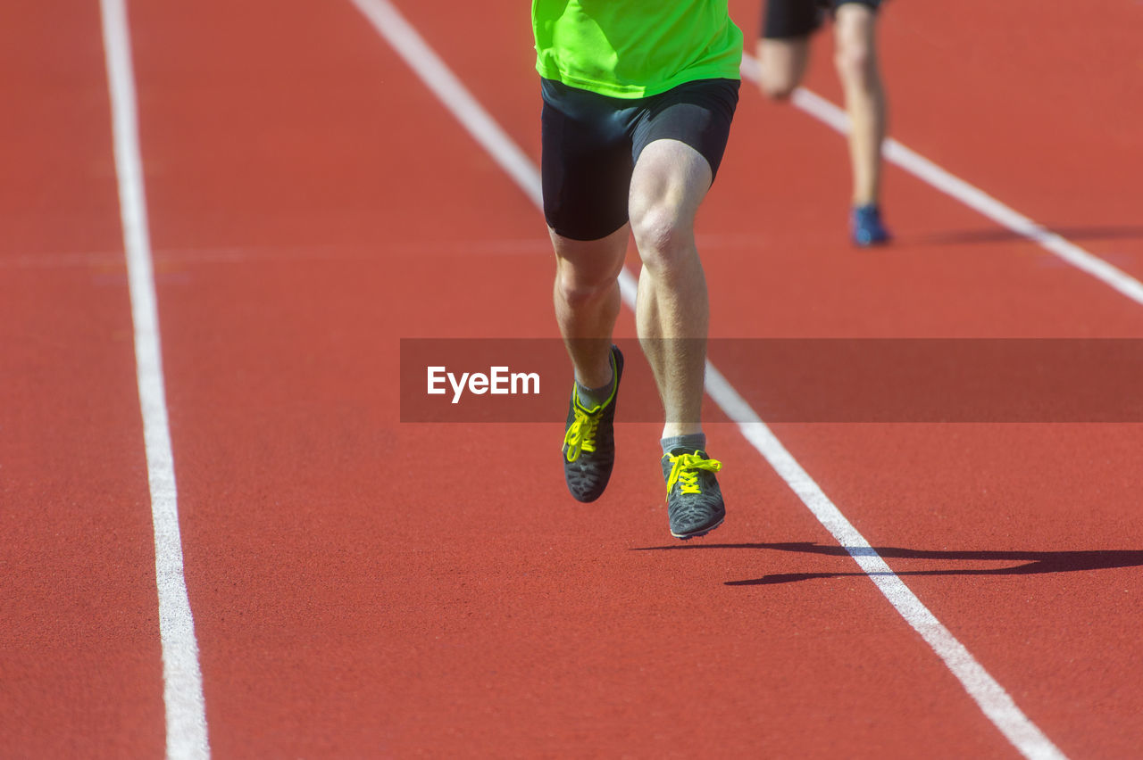 LOW SECTION OF MAN RUNNING ON RED FLOOR